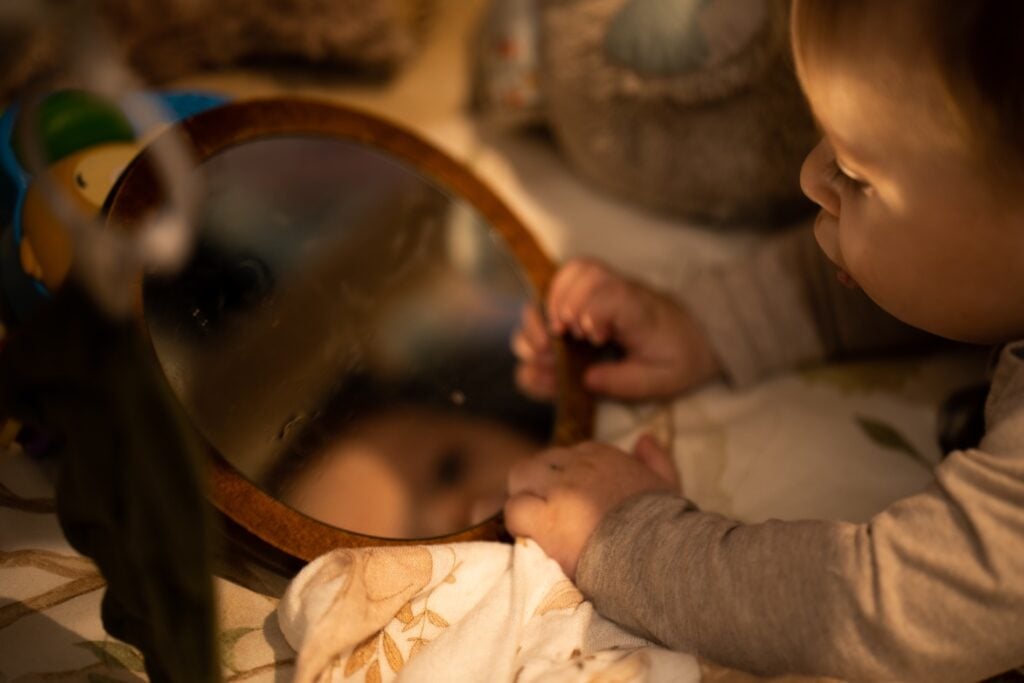 Bébé jouant avec un miroir d’éveil en bois, activité sensorielle inspirée de la pédagogie Montessori