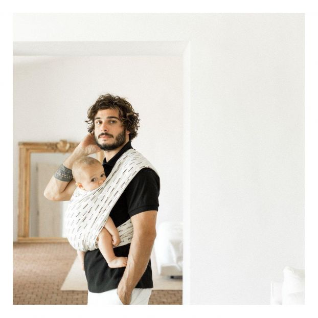 Écharpe de portage bébé en tissu léger portée par un jeune père à la maison