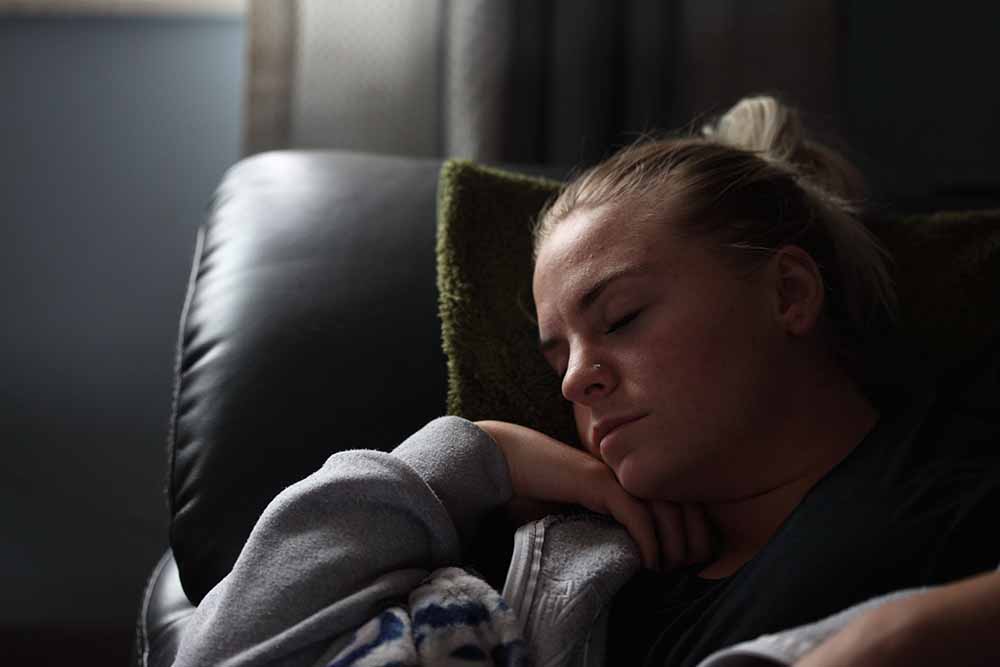 Femme enceinte endormie dans un fauteuil, illustrant la nécessité de siestes pour lutter contre la fatigue de grossesse.