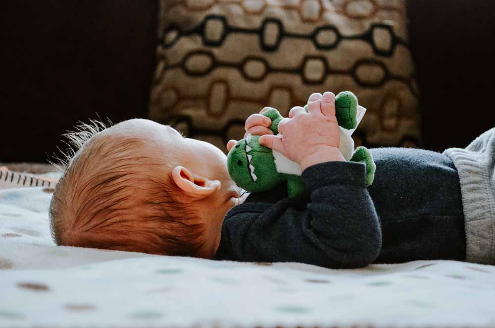 Bébé allongé tenant un doudou, moment calme à la maison avant la garde