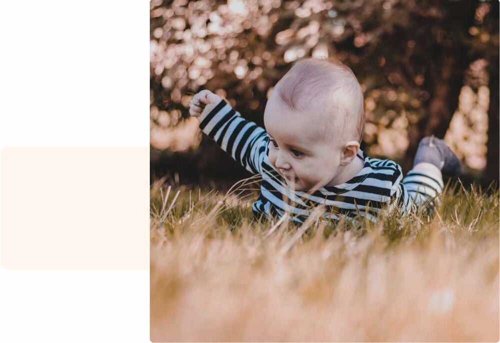 Bébé allongé dans l’herbe qui rampe et découvre la nature, activité bébé 7 mois favorisant la motricité