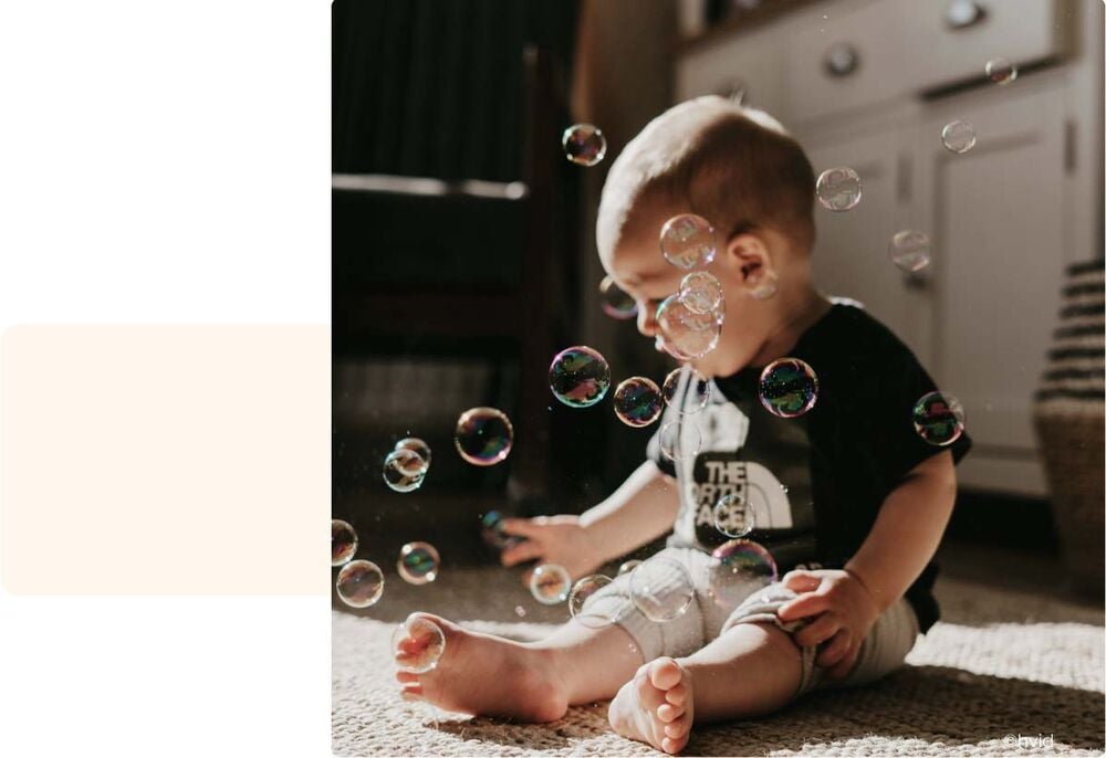 Bébé entouré de bulles de savon flottantes, activité sensorielle bébé 11 mois