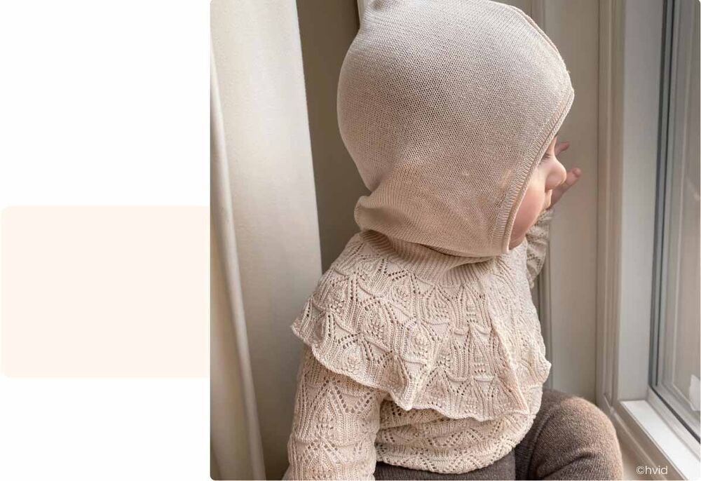 Bébé assis près d’une fenêtre observant dehors, activité bébé 12 mois, curiosité