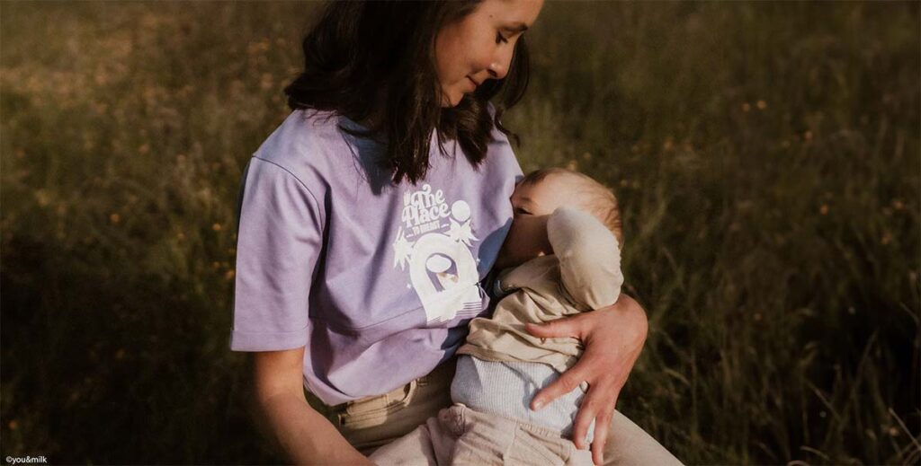 jeune maman en t-shirt lilas allaite son nourrisson en exterieur