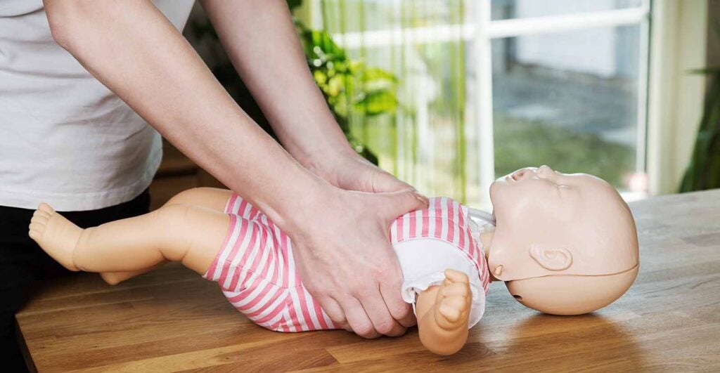 Simulation des gestes premiers secours enfant pour agir face à un étouffement, montrant comment vérifier la bouche et pratiquer les techniques adaptées