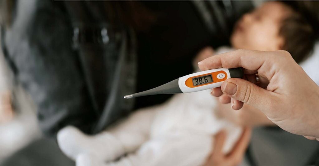 Parent vérifiant la température d’un bébé avec un thermomètre digital, illustrant les gestes premiers secours bébé et enfant à connaître en cas de fièvre ou symptômes inquiétants