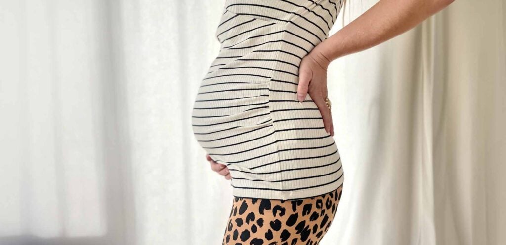 Femme enceinte tenant son ventre, période précédant l’arrivée de l’enfant et l’importance de connaître les aides financières disponibles avant l’accouchement