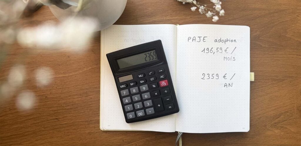 Calculatrice sur un carnet indiquant les montants mensuels et annuels de la PAJE adoption, exemple concret d’aides financières adoption enfant