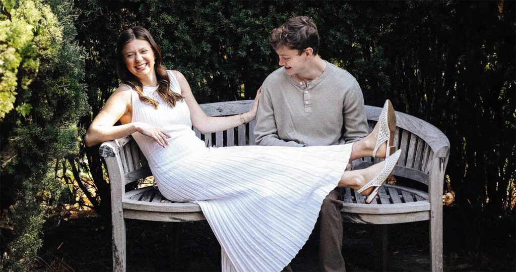 Femme enceinte et son partenaire partageant un moment complice sur un banc de jardin pendant la grossesse