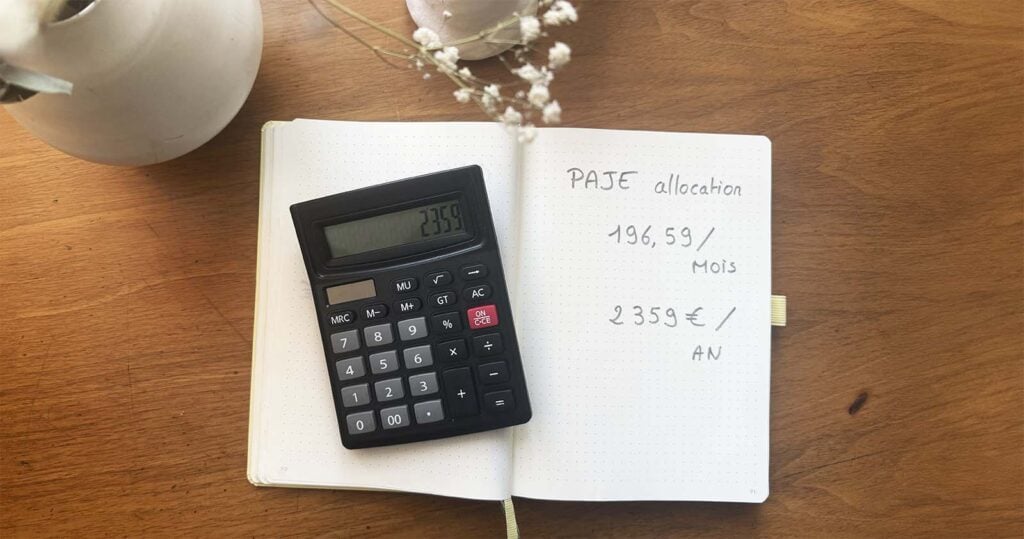 Calculatrice posée sur un carnet mentionnant le montant annuel de la PAJE, exemple concret d’aides financières naissance bébé que les familles peuvent recevoir