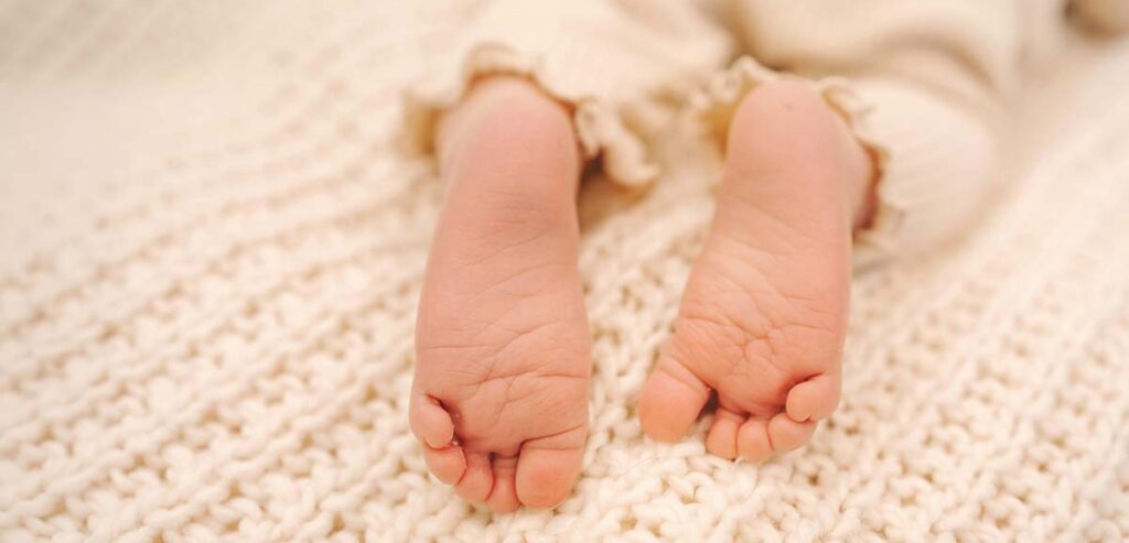 Pieds d’un nouveau-né sur une couverture, image douce pour illustrer les informations sur le congé maternité