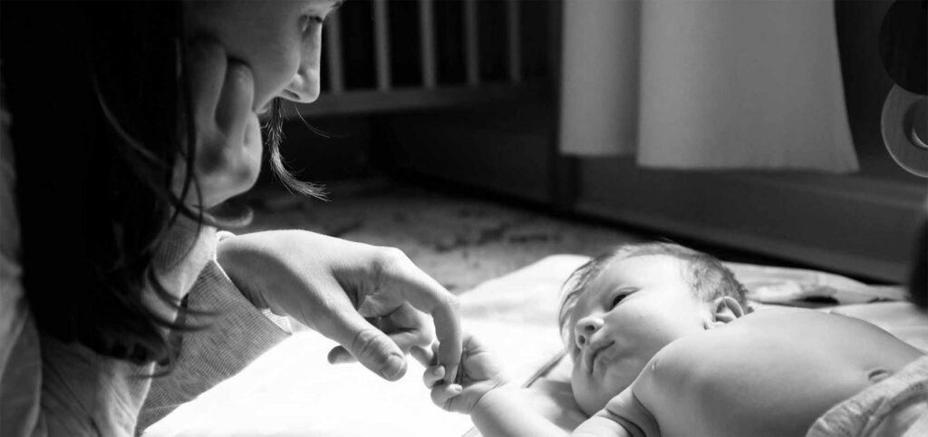 Soins post-césarienne : mère tenant la main de son nouveau-né, accompagnement et rétablissement après accouchement par césarienne