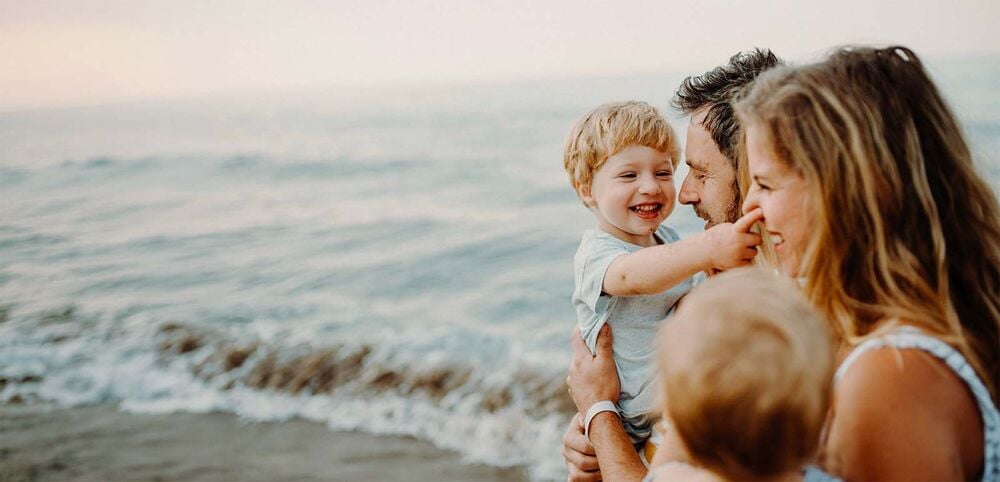Parents et deux enfants complices au bord de la mer, famille recomposée et nouvel enfant, gérer les émotions de la fratrie existante