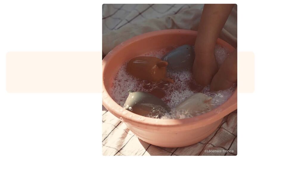 Pieds de bébé dans une bassine d'eau savonneuse en plein air, jeux camping bébé, activités eau et bain de pieds pour occuper bébé en extérieur