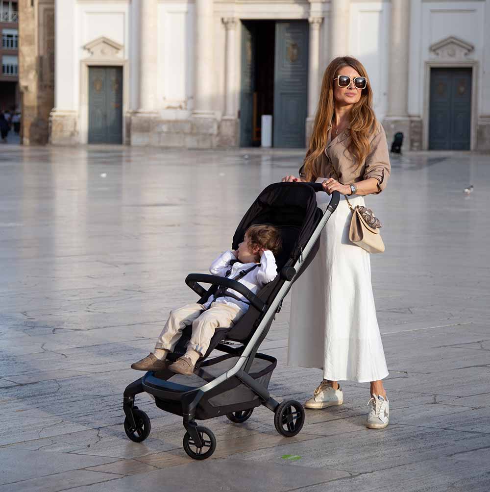 Maman et enfant endormi dans sa poussette Maxi-Cosi sur une place, meilleure poussette voyage Maxi-Cosi compacte pour partir en famille