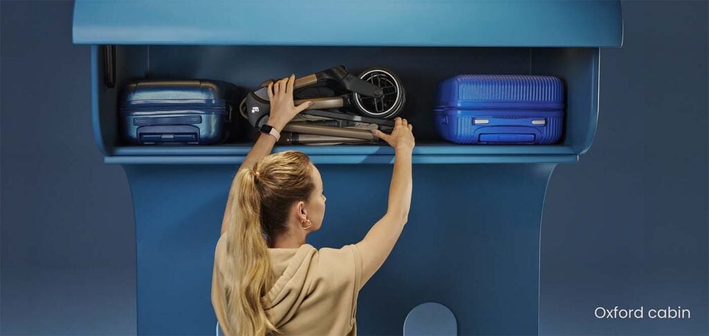 Poussette Maxi-Cosi Oxford pliée rangée dans le casier avion entre deux valises, meilleure poussette cabine Maxi-Cosi ultra-compacte pour voyager en avion