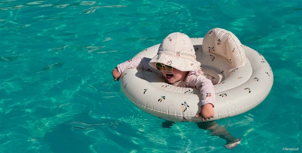 Bébé dans une bouée avec chapeau et lunettes de soleil à la piscine, pourquoi protéger bébé du soleil même dans l'eau