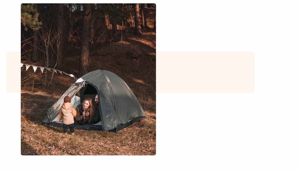 Couple avec un jeune enfant devant l'entrée d'une tente en forêt, préparation camping avec bébé, organiser le séjour en famille sous tente