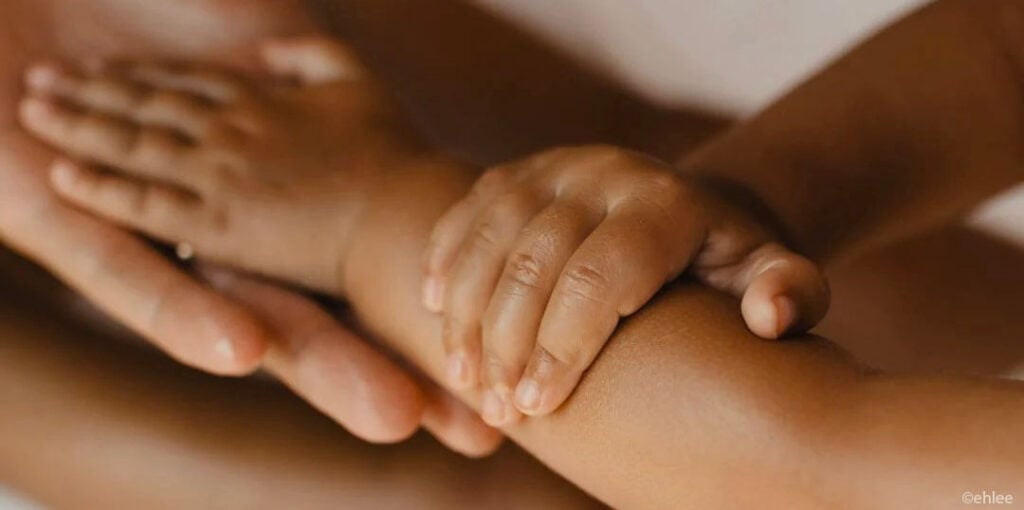 Main de bébé agrippant le bras de sa maman, protection bébé chaleur, l'importance de surveiller la température corporelle du nourrisson