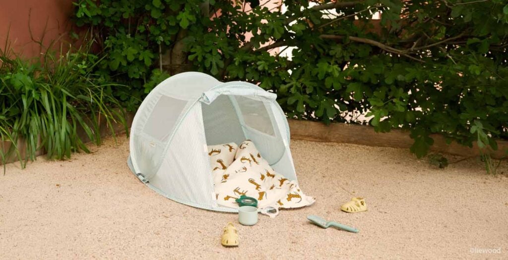 Tente anti-UV bébé installée sur le sable, protéger bébé du soleil à la plage avec une tente ombrage adaptée aux nourrissons