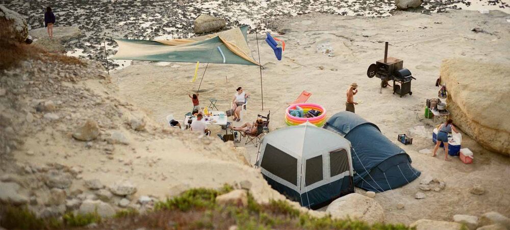 Vue aérienne d'un campement familial sur la plage avec piscine gonflable et tente, quel âge minimum pour camper avec bébé, partir au camping en famille dès les premiers mois